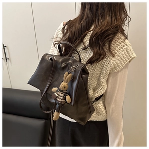 Brown PU leather backpack with cute rabbit charm shown worn on a model's back