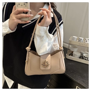 Detail of beige underarm bag with gold flower buckle and textured leather finish