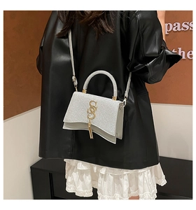 Detail of silver sequin crossbody bag featuring a gold double-S clasp and fringe tassel