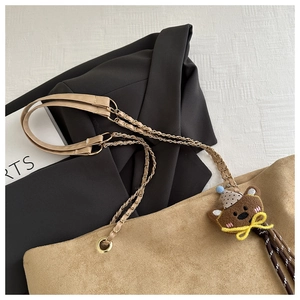 Dettaglio borsa tote in pelle scamosciata kaki con tracolla a catena e ciondolo orso