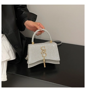 Detail of silver sequin handbag featuring gold SS logo and elegant tassel charm