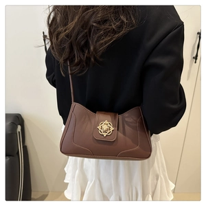 Detalle de bolso bandolera vintage marrón con cierre floral dorado y correa fina en modelo