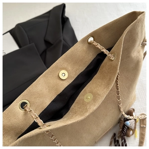 Dettaglio della borsa a secchiello in camoscio kaki con chiusura magnetica e catena