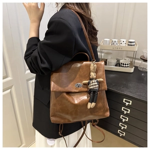 Detail of brown vintage leather backpack featuring a silver clasp and a cute rabbit charm