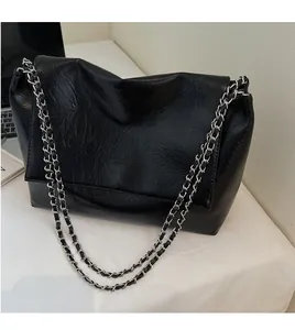 Detail of glossy wrinkled leather shoulder bag featuring silver chain strap and logo