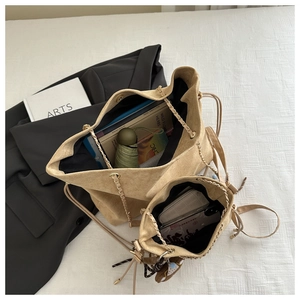 Dettaglio borsa tote in pelle scamosciata kaki e borsa a secchiello con catena dorata