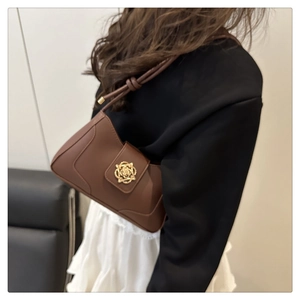 Close-up of a brown leather shoulder bag with a gold flower buckle worn by a woman