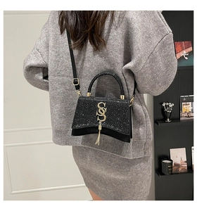 Detail of glitter black hourglass bag with golden SSS logo on a model side view