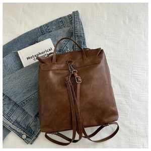 Detail of vintage brown PU leather backpack featuring metal hooks and adjustable straps