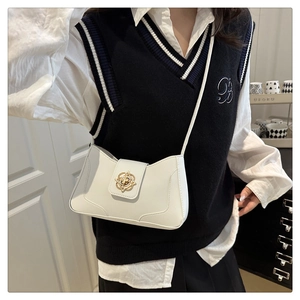 Detail view of a white leather crossbody bag featuring a gold floral clasp and black strap