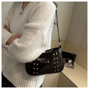 Vue détaillée du sac sous le bras en cuir verni marron avec rivets argentés et bandoulière