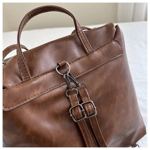 Detail of vintage brown PU leather backpack handle and adjustable metal buckle straps