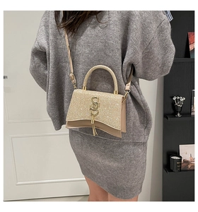 Close-up of champagne gold sequined crossbody bag with metal top handle and tassel
