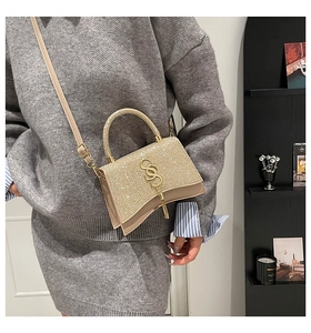 Detail of glitter champagne gold crossbody bag showing hourglass curved base and S-logo