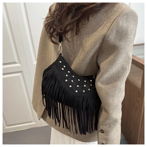 Detail of bohemian black suede bag showing golden rivets and long hanging fringes
