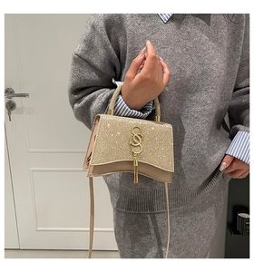 Detail of champagne gold sequined handbag with gold S-logo and fringe tassel charm