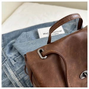 Close-up of vintage brown leather backpack texture with dark grey metallic buckle details