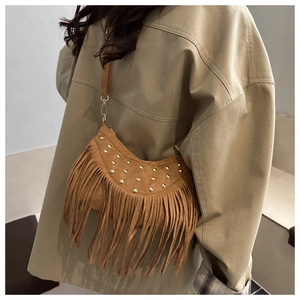Close-up of brown suede tassel handbag with round golden studs on model shoulder