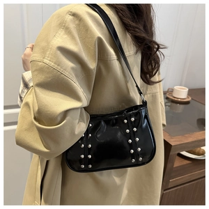 Détail du sac à bandoulière en cuir verni noir avec des clous argentés de style Y2K
