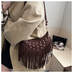Detail of brown suede crossbody bag featuring gold studs and long fringe tassels