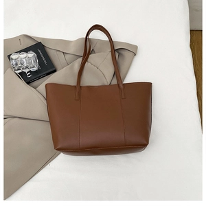 Détail d'un cabas en cuir mat marron foncé avec coutures verticales et longues anses