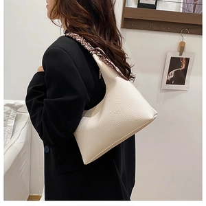 Detail der cremeweißen Hobo-Tasche aus Litschileder mit Seidenschal am Griff für Damen