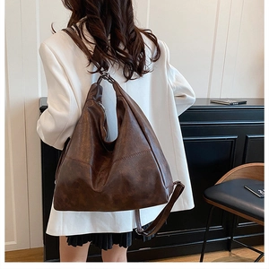 Detail of dark brown faux leather hobo bag showing stitching and metal zipper texture