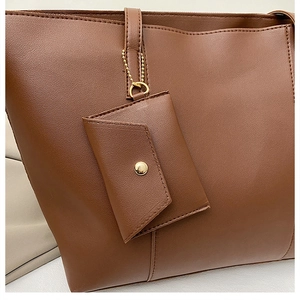 Gros plan du sac cabas en cuir grainé marron avec petite pochette et détails dorés