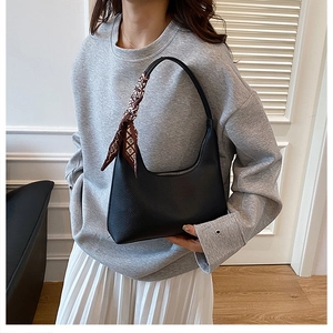Détail du sac hobo en cuir grainé noir avec foulard en soie sur la poignée