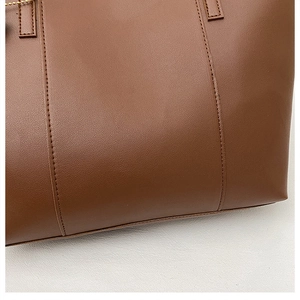 Gros plan du sac cabas en cuir marron montrant la texture grainée et la couture