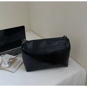Close-up of black glossy crinkle leather tote bag with silver metal chain strap detail