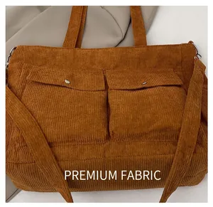 Detail of brown corduroy tote bag showing front utility pockets and ribbed texture