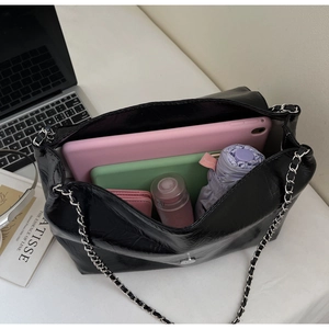 Detail showing the large interior capacity of this black chain tote bag with daily essentials