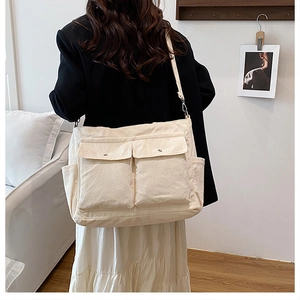 Detail of soft off-white corduroy tote bag with dual front pockets and shoulder strap