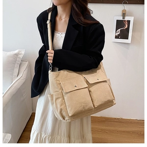 Detail of beige corduroy tote bag showing multiple pockets and adjustable shoulder strap