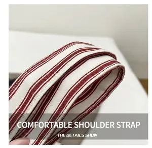 Close-up of red and white striped canvas shoulder strap with reinforced double stitching
