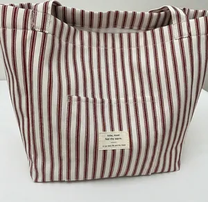 Detail of red and white striped canvas tote bag showing the exterior pocket and fabric label