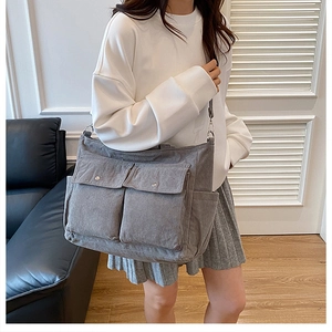 Detail view of grey corduroy tote bag with double front pockets on female model