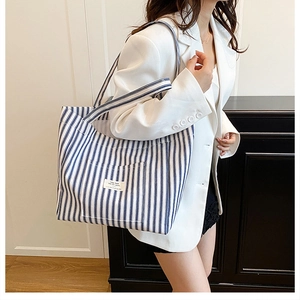 Detail of blue and white striped canvas tote bag with woven label and long straps