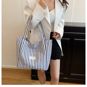Detail view of the vertical blue and white striped canvas tote with its textile logo patch
