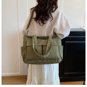 Detail of olive green corduroy tote bag featuring front pockets and side storage pouch