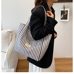 Detail of blue and white striped canvas tote bag showing textured fabric and minimalist tag