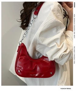 Detail of red crescent hobo bag with silver chain strap and fashion logo on shiny PU leather