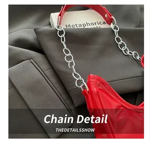 Detail of red patent leather shoulder bag with silver metal chain links and handle