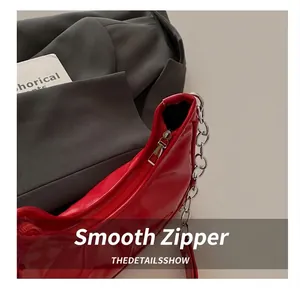 Close-up of bright red patent leather shoulder bag featuring silver chain and smooth zipper