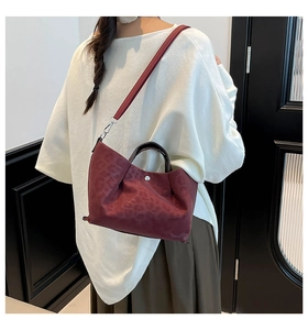 Detail of dark red leopard print tote bag featuring brown handles and silver metal buckle