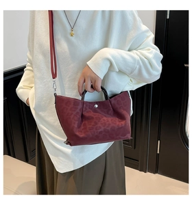 Detail of burgundy leopard print handbag featuring silver snap closure and black top handle