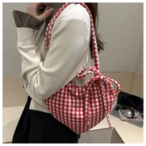 Détail du sac à main coeur vichy rouge et blanc avec noeud latéral porté par un mannequin