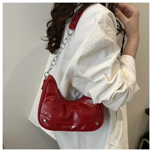 Detail of red leather dumpling bag with silver chain strap and metal rivet accents