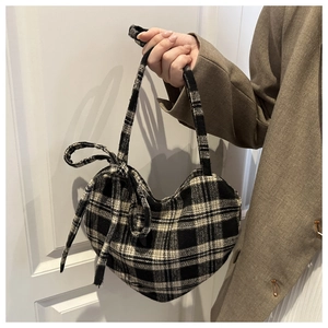Détail d'un sac cabas en forme de cœur en tweed à carreaux noir et blanc avec nœud décoratif